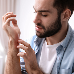 Young man scratching hand indoors